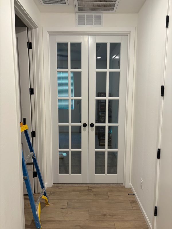 White double doors with glass panels in a hallway.