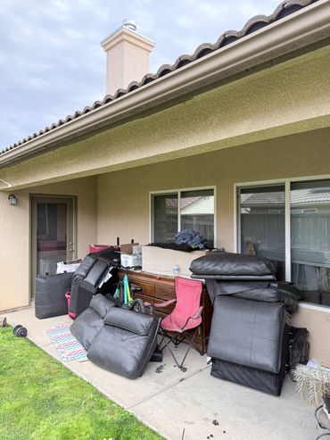Outdoor patio cluttered with furniture cushions, a bicycle, and a folding chair.