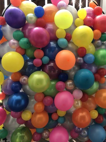 A fun filled balloon wall filled with bright colours.