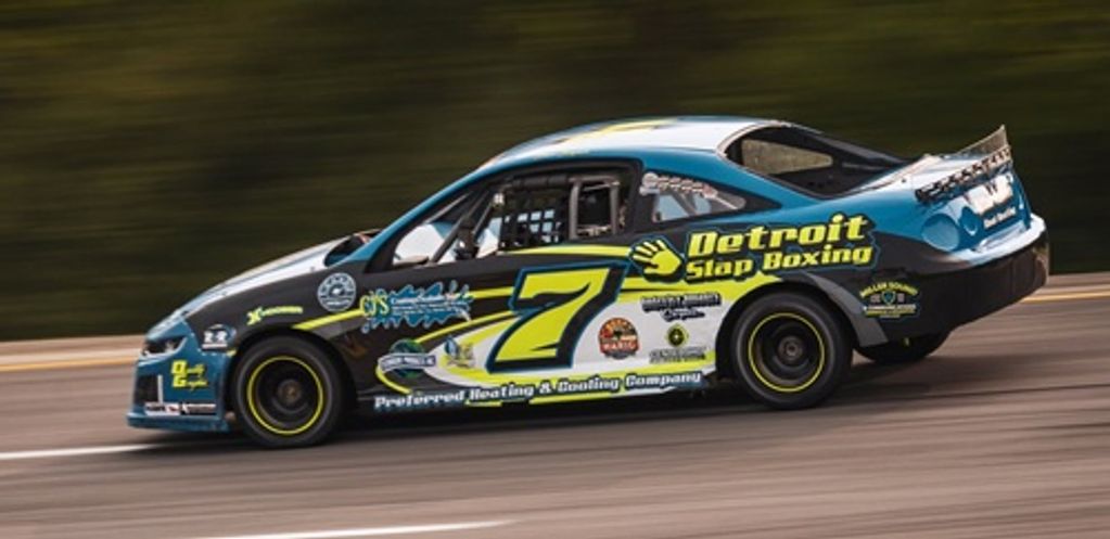 Race car number 7 speeding on the track with Detroit Slap Boxing sponsorship.