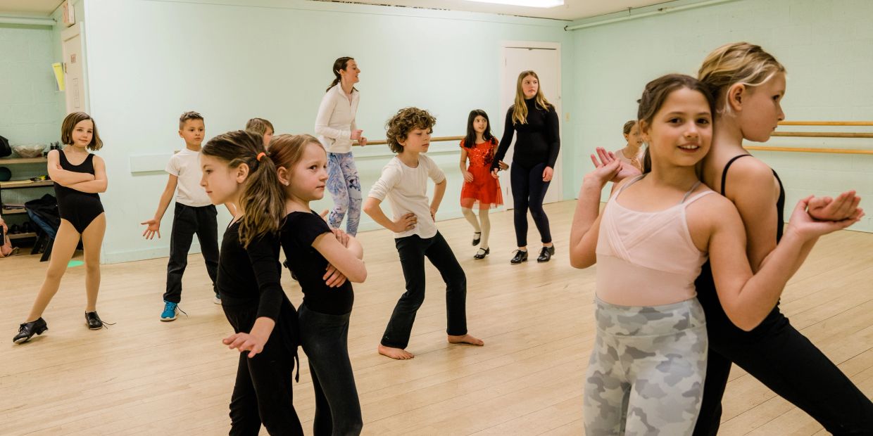 Children participating in a lively dance class in a studio.