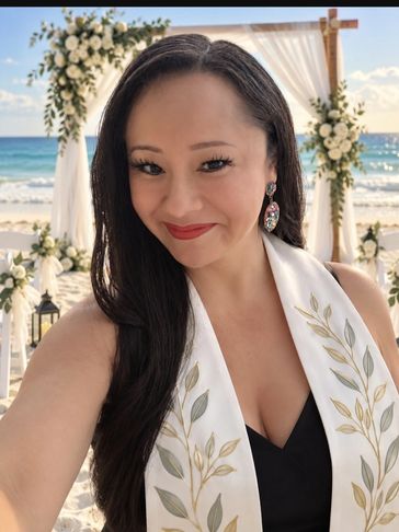 Woman taking a selfie at a beach wedding.