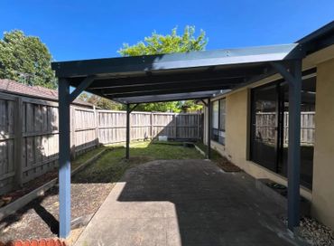 Backyard patio with a pergola and fenced garden area.