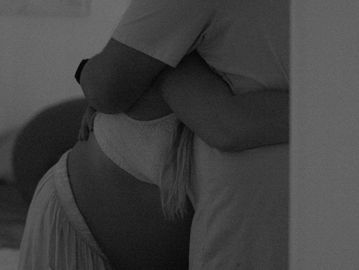 Un couple s'enlace avec un ventre de femme enceinte visible.