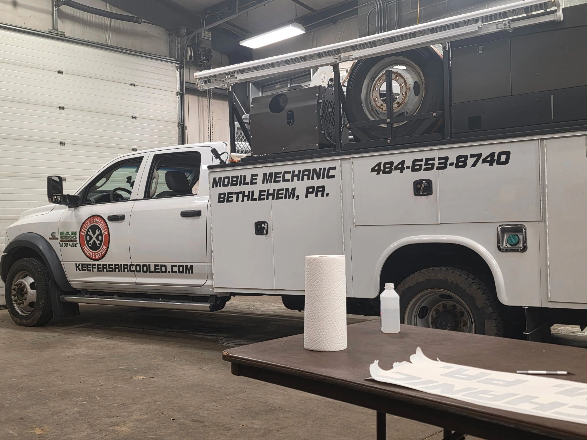 White mobile mechanic truck with company branding inside a garage.