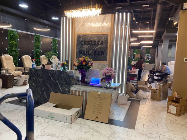 Interior of Chelsea Nail Bar with chairs, flowers, and people.