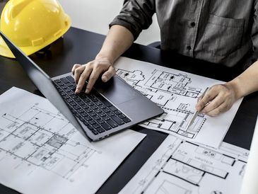 Engineers are typing on a laptop keyboard to review the design of the house before editing it