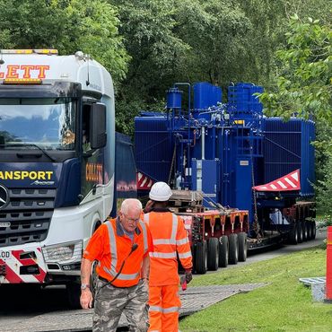 Blue artic lorry transporting something heavy and two men