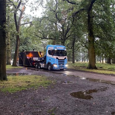 Lorry transporting a heavy item in a woodland