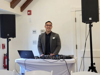 DJ standing behind a table with his sound equipment smiling.