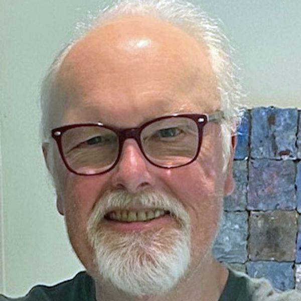 Smiling elderly man with white hair and glasses.