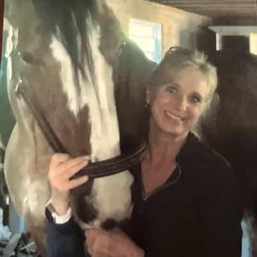 Woman smiling while hugging a horse indoors.