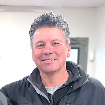 Smiling middle-aged man in a black jacket indoors.