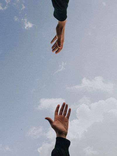  2 arms reaching  to each other to clasp hands w/sky background.  
Unsplash image by Youssef Naddam.