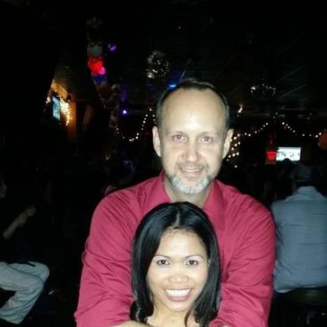 Couple smiling and embracing at a dimly lit party or bar.