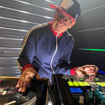 DJ mixing music on turntables and mixer in a dimly lit room.