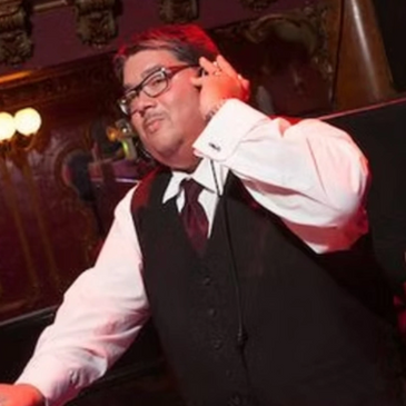 A DJ in a formal outfit mixing music at an elegant venue.