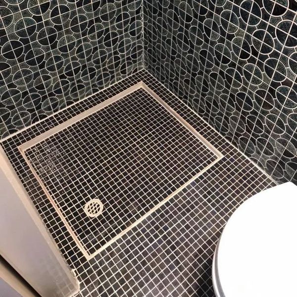 Bathroom floor and walls with black tiles and white circular patterns.