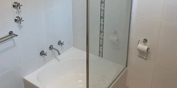 Clean modern bathroom with a bathtub and glass shower partition.