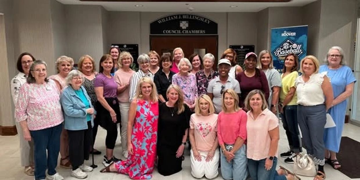 Group of women posing in a council chamber lobby.