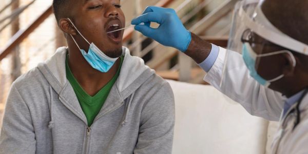 Man getting oral swab test from healthcare worker.