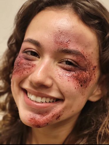 Smiling woman with exfoliating scrub on her face.