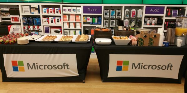 Microsoft-branded tables with snacks and drinks in a tech store.