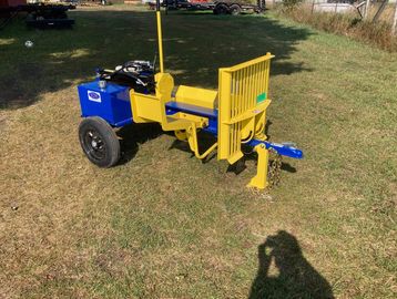A compact yellow and blue log splitter on grass under sunlight.