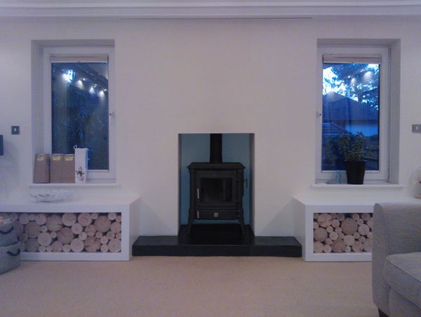 A black woodburner installed in a white fireplace setting.