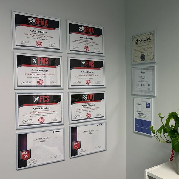 Wall displaying multiple framed certificates and awards.