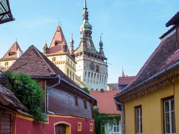 Charming medieval street with colorful houses and a clock tower in the background.