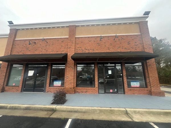 Empty brick storefronts with signs indicating spaces for lease.