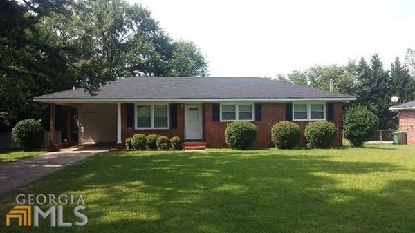 Single-story brick house with a well-maintained front lawn and shrubs.
