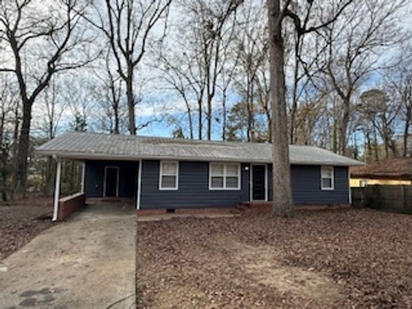 Single-story house with carport surrounded by leafless trees.