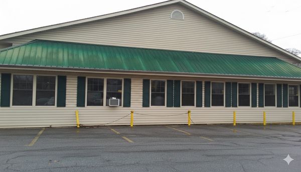 Long building with green roof and multiple windows along a parking lot.