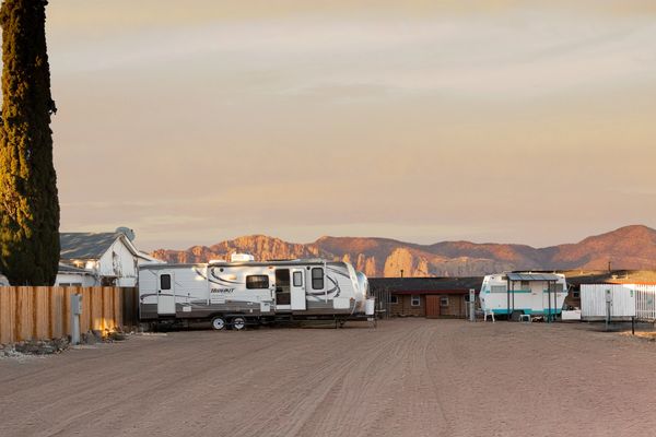 RVs and trailers parked in a desert area with mountains.