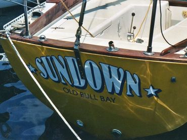 Yellow boat named SUNDOWN docked in water at Old Bull Bay.