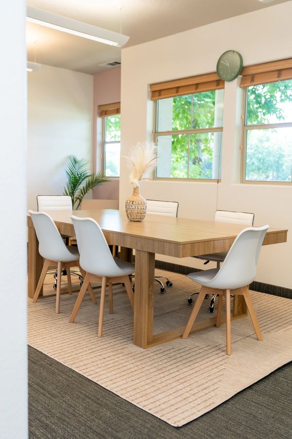 Bright, modern conference room with wooden table and white chairs.