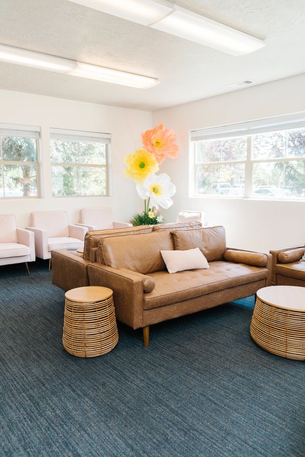 Bright and cozy waiting room with leather sofas and oversized floral decor.