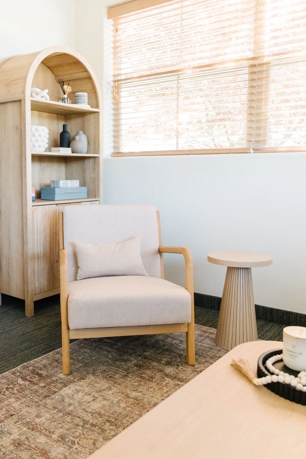 Cozy beige armchair with wooden frame in a sunlit room with minimalist decor.