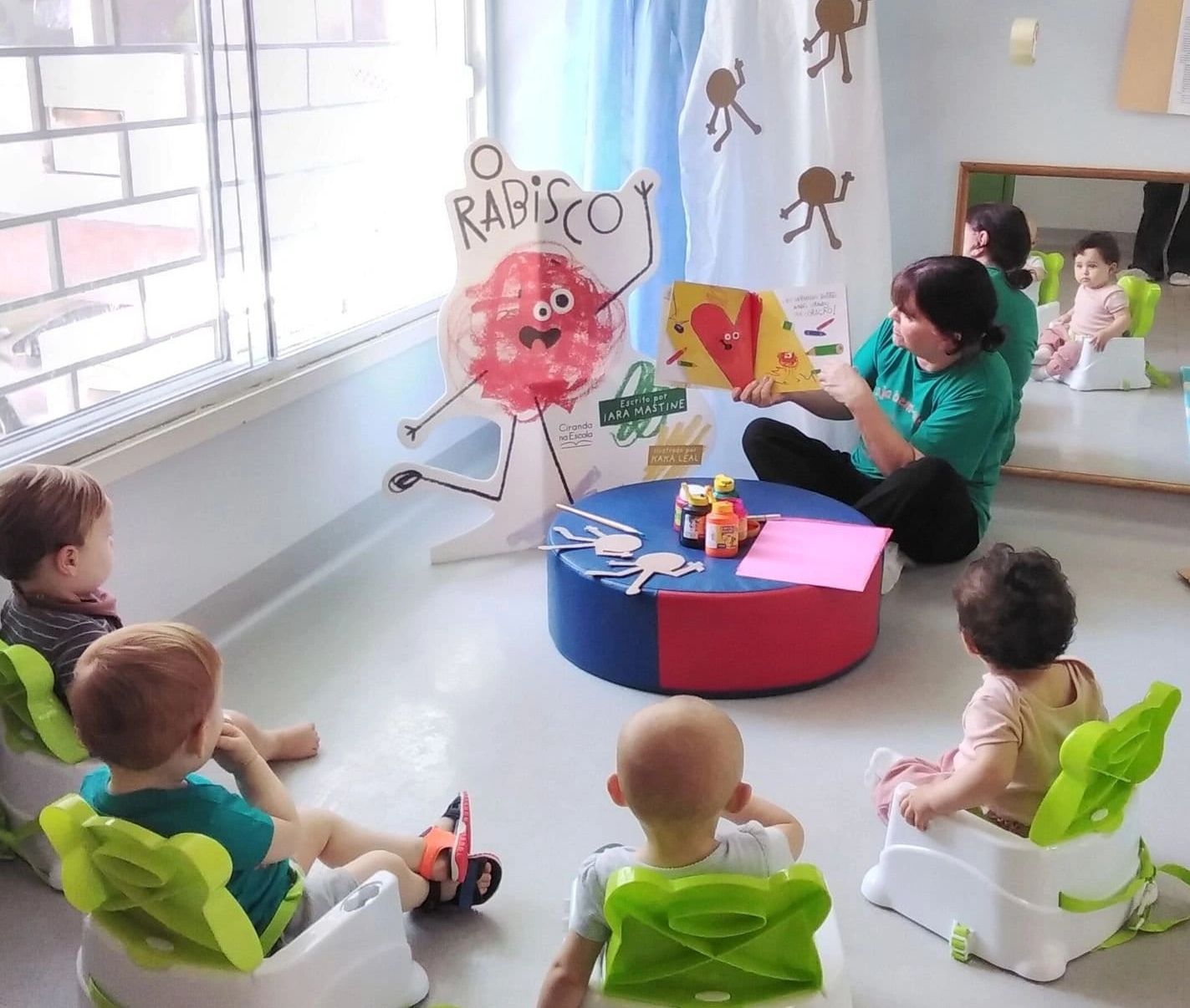 Teacher reading to toddlers seated in a classroom circle.