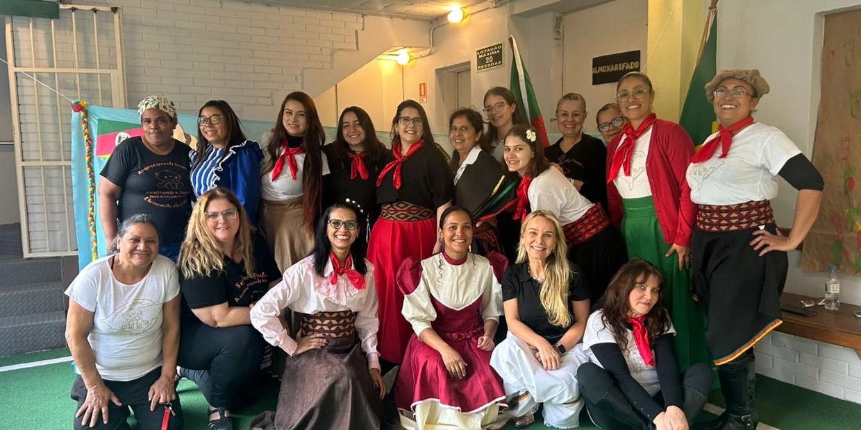 Group of women in traditional attire posing indoors on green carpet.