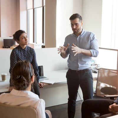 Serious business man team leader coach mentor talk to diverse business people in office