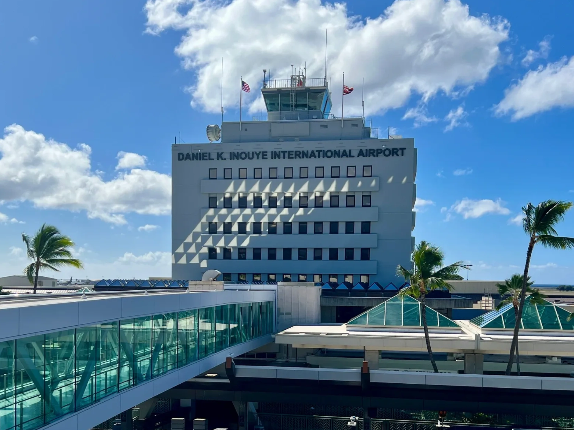 Daniel K. Inouye International Airport under a bright blue sky with palm trees.