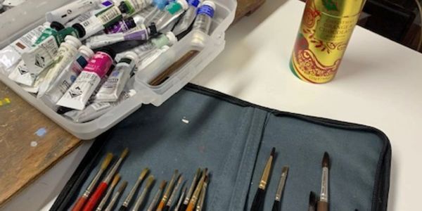 Art supplies including paint tubes and brushes neatly arranged on a table.