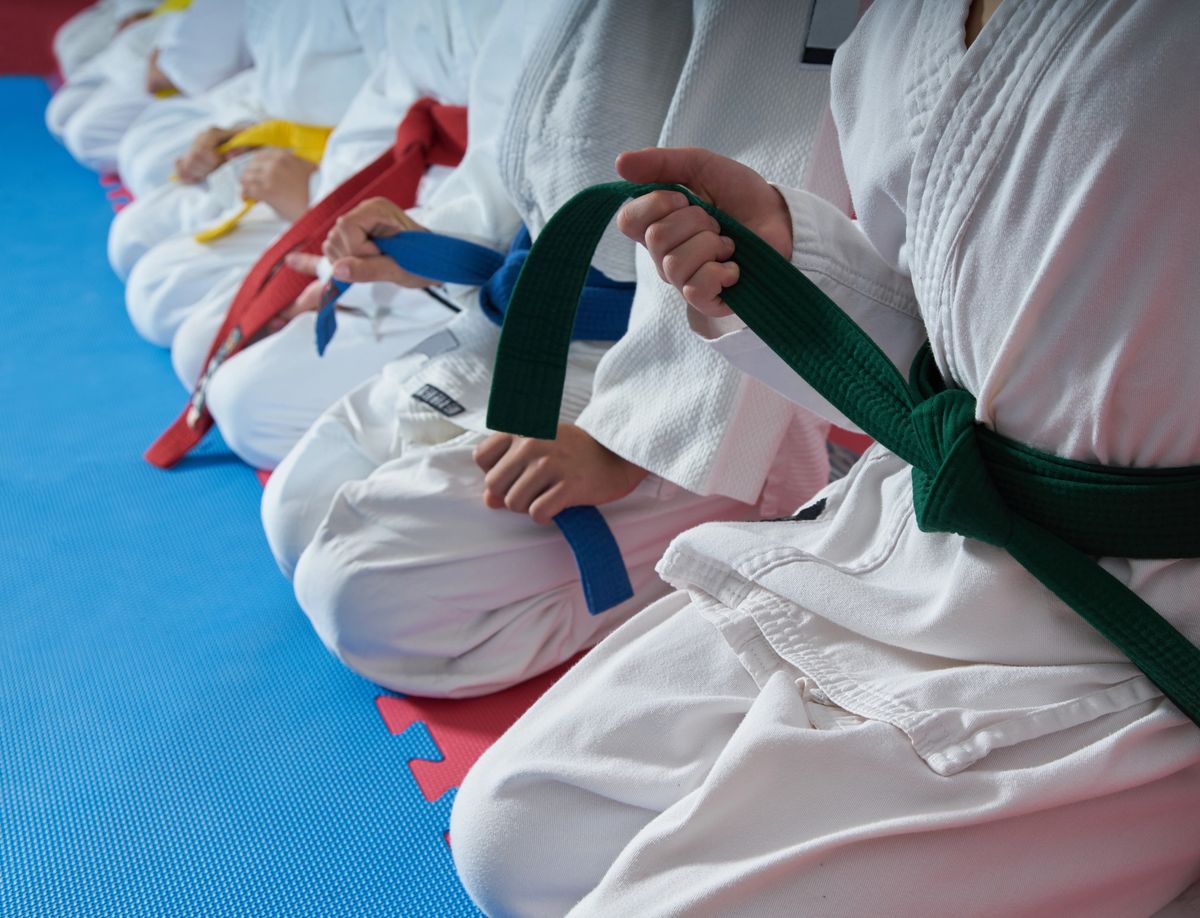 Karate students sitting on mats.