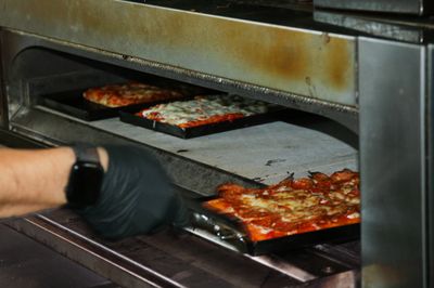 Person taking pizzas out of an oven.