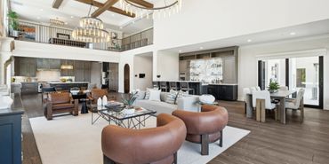 Spacious modern living room with leather chairs and a large kitchen.