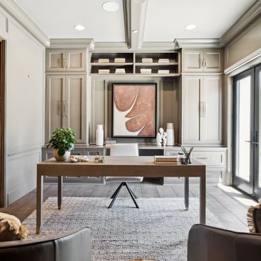 Modern home office with beige desk, built-in shelves, and abstract art.