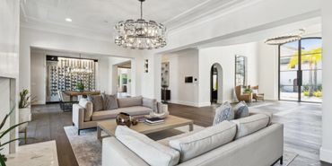Modern open living room with neutral sofas and elegant lighting.